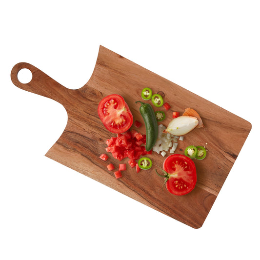 WOOD CURLS rectangular acacia wood chopping board with curved edges, handle, and fresh chopped vegetables on top.