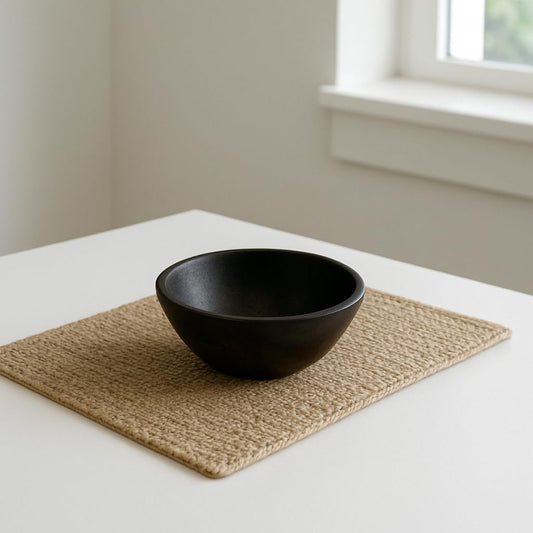 WOOD CURLS small round serving bowl made of dark brown mango wood sitting on a textured woven placemat