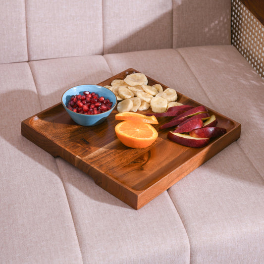 WOOD CURLS square mango wood serving platter holding a small bowl of pomegranate seeds, sliced bananas, and apples.