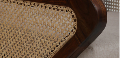 Close-up of WOOD CURLS Aarav sofa armrest featuring handwoven cane paneling and rich provincial teak Sheesham wood.