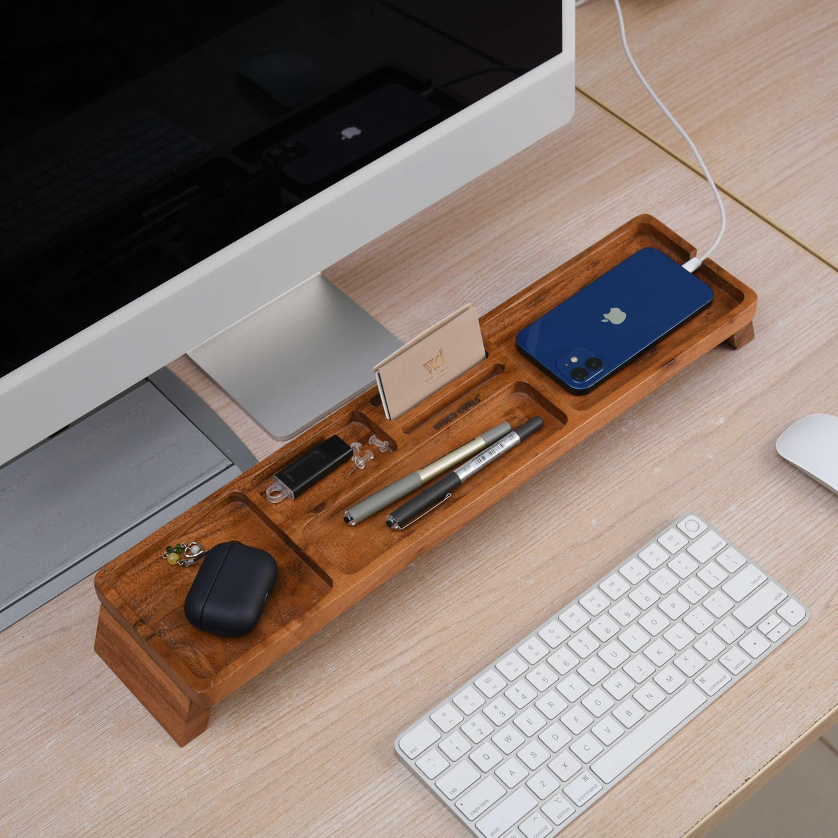 WOOD CURLS handcrafted acacia wood desk organizer with multiple compartments holding stationery and gadgets on a desk.
