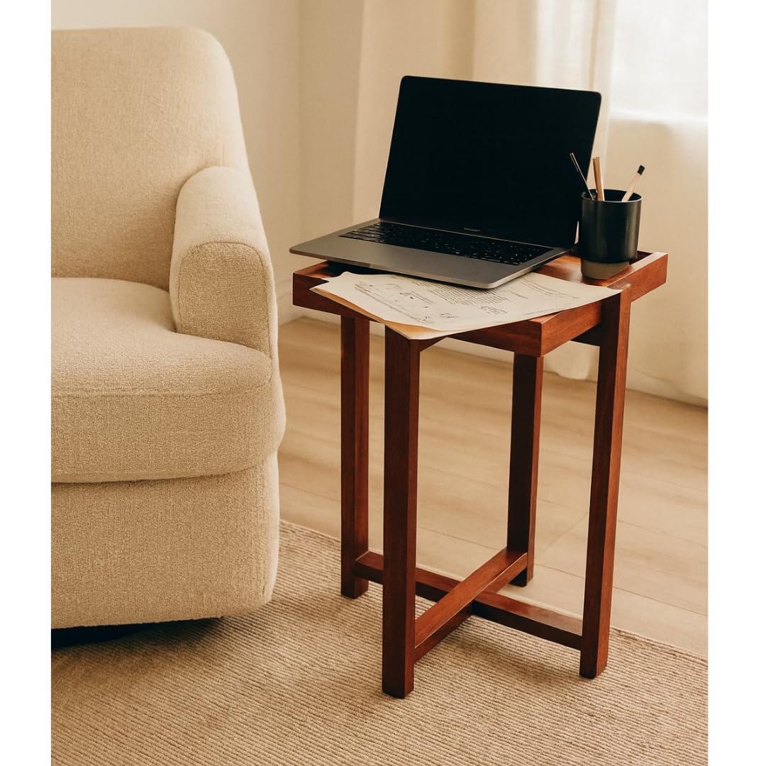 WOOD CURLS Enigma square acacia wood center table with a laptop and stationery, placed next to a beige armchair.