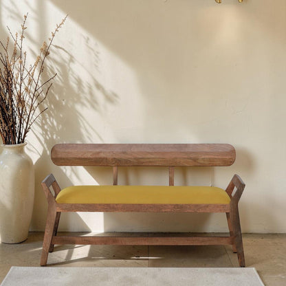 WOOD CURLS Alderra mango wood bench with a mustard yellow velvet seat, backrest, and tapered legs in a bright room.