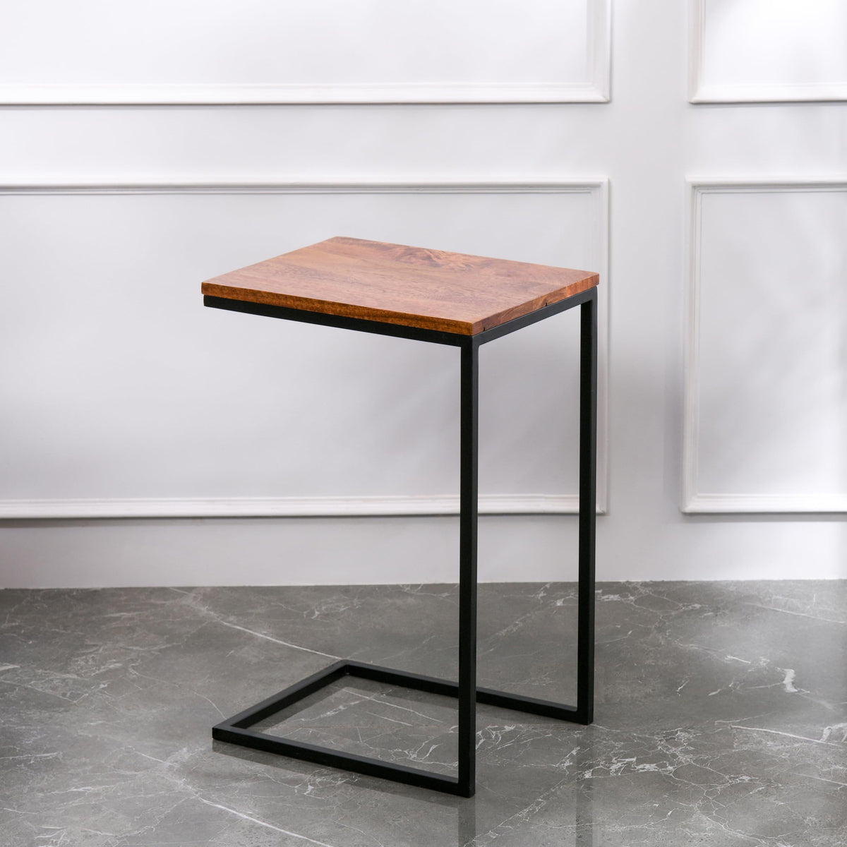 WOOD CURLS Odyssey C-shape side table with a warm mango wood top and a durable black iron frame on a marble floor.