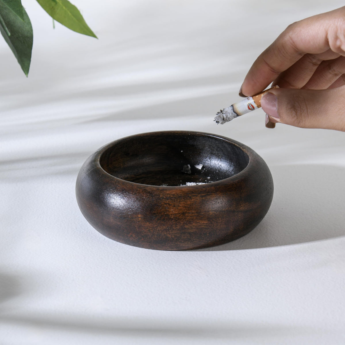 WOOD CURLS handcrafted dark brown wooden ashtray with a deep bowl design being used on a white surface