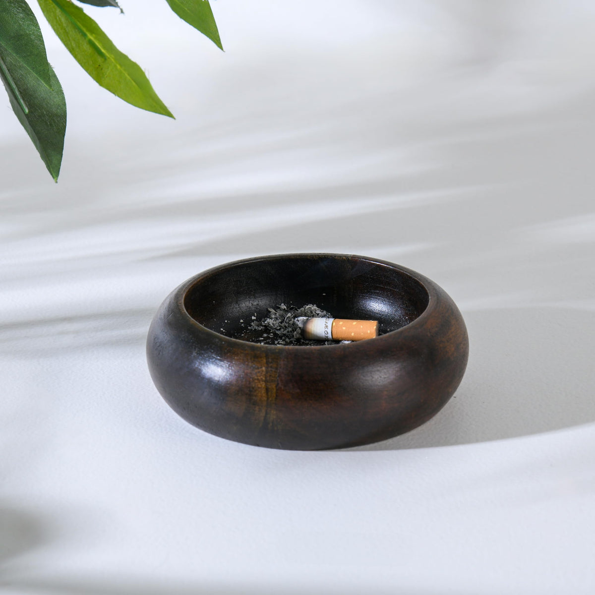WOOD CURLS handcrafted dark brown wooden ashtray with a deep bowl design and a cigarette resting inside