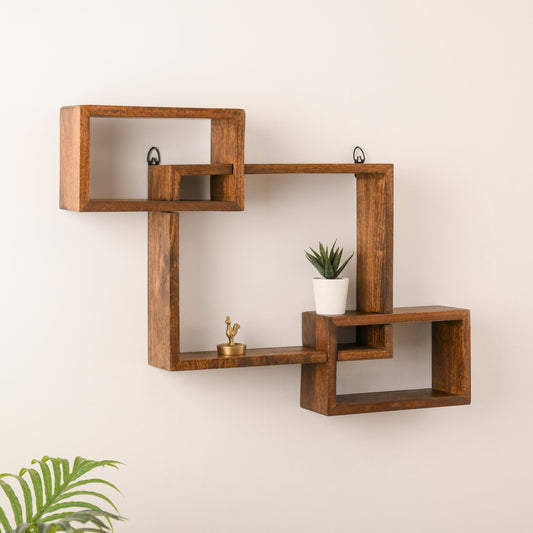 WOOD CURLS intersecting geometric wall shelf made of solid brown mango wood displaying a small plant and figurine.
