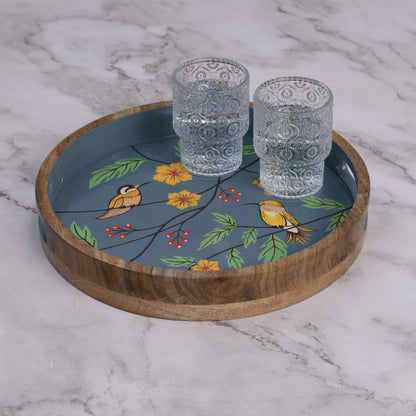 WOOD CURLS round mango wood serving tray with hand-painted birds, yellow flowers, and berries on a slate blue base.