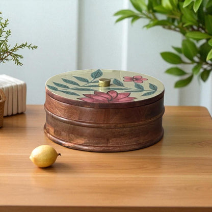 WOOD CURLS handcrafted mango wood storage container with a round shape and hand-painted floral lid on a wooden table