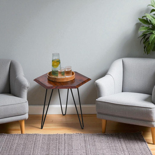 WOOD CURLS hexagon side table made of sheesham wood with black metal hairpin legs between two grey armchairs