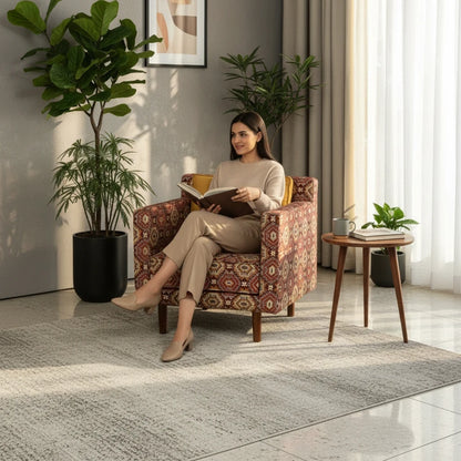 Woman reading in a WOOD CURLS Ikat fabric accent armchair with geometric patterns and wooden legs in a bright room.