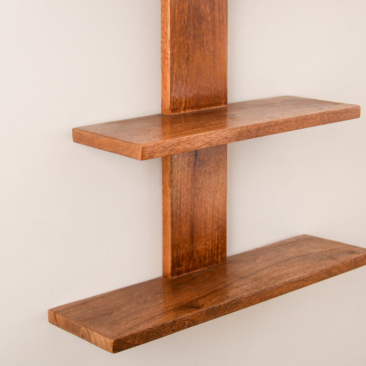 WOOD CURLS 3-tier wall-mounted shelf made of natural brown mango wood with visible grain patterns on a white wall.