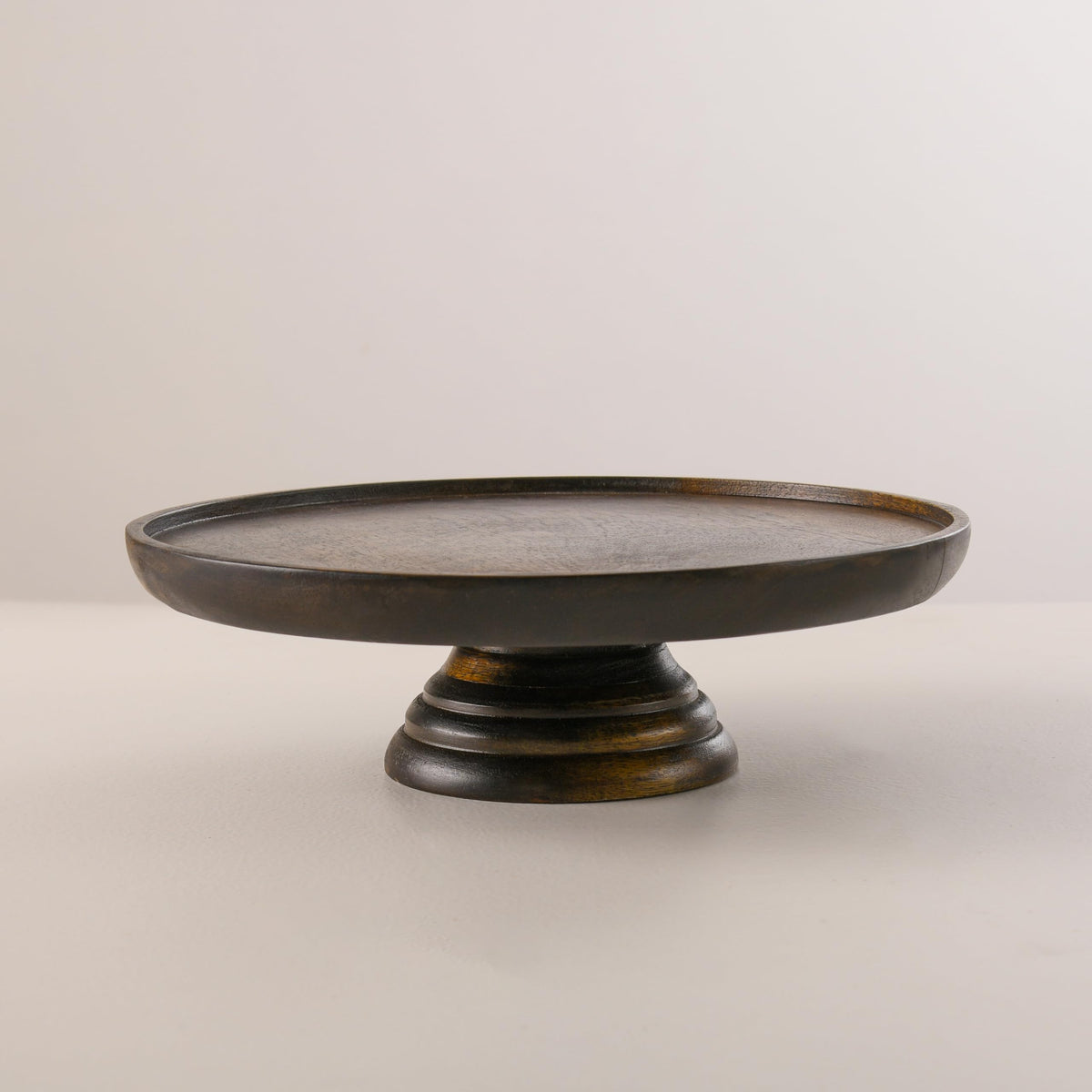 WOOD CURLS round mango wood cake stand with a rich walnut finish and sturdy pedestal base for dessert display.