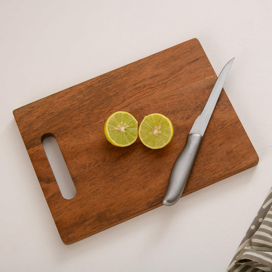 WOOD CURLS rectangular mango wood chopping board with a knife and sliced lemon on a white surface