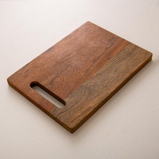 WOOD CURLS rectangular mango wood chopping board with a built-in handle and natural wood grain finish.