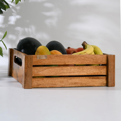 WOOD CURLS handcrafted mango wood crate filled with fresh fruits like bananas and melons on a white surface