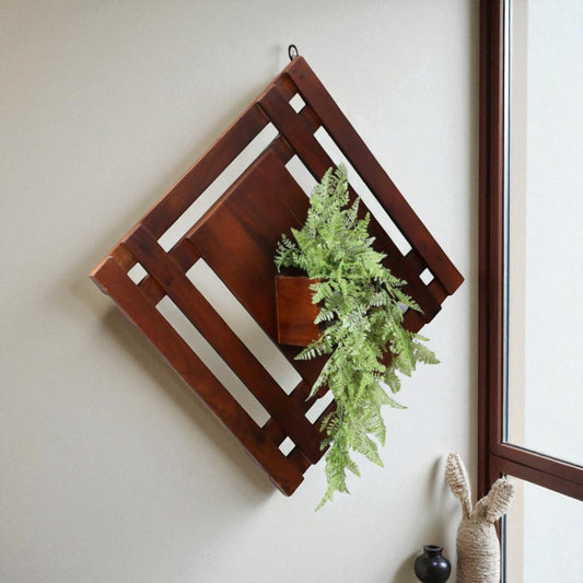 WOOD CURLS diamond-shaped mango wood wall shelf with a decorative green fern plant mounted on a neutral wall.