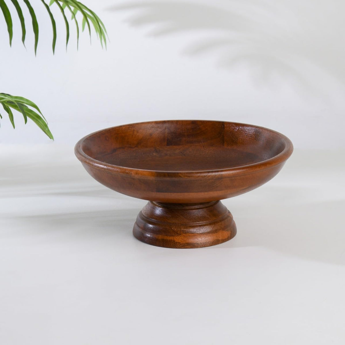 WOOD CURLS handcrafted mango wood pedestal fruit bowl with a warm natural grain finish on a white background