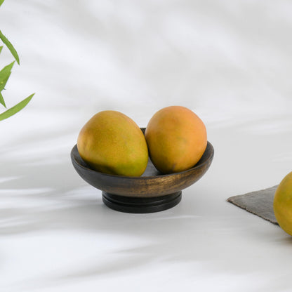WOOD CURLS small mango wood pedestal bowl in dark brown holding two fresh mangoes on a white surface