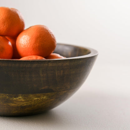 WOOD CURLS 10-inch round mango wood serving bowl with a walnut finish, filled with fresh oranges on a neutral surface.