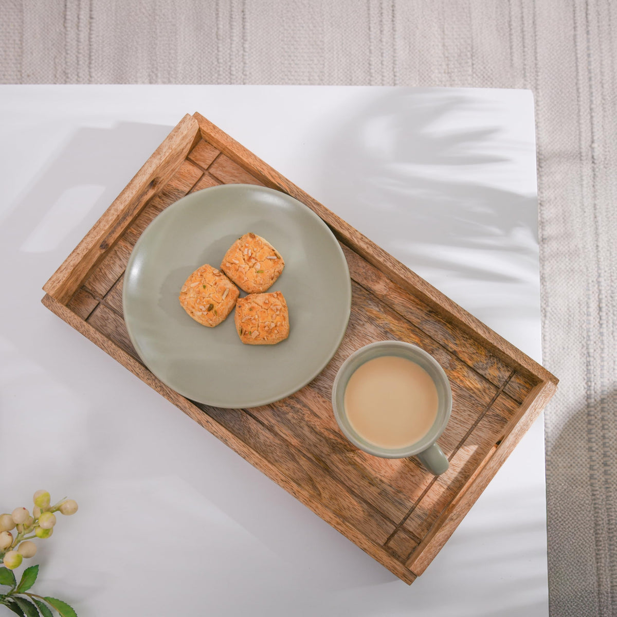 WOOD CURLS rectangular mango wood serving tray with handles holding a sage green plate of cookies and a tea cup