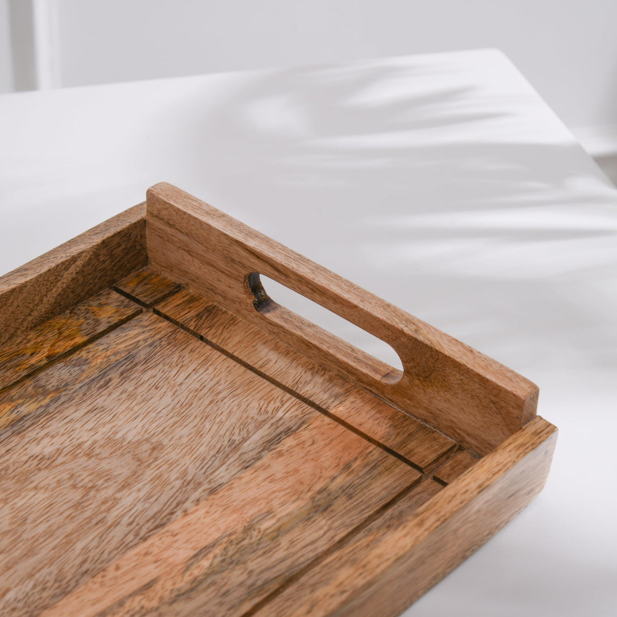 WOOD CURLS rectangular serving tray made of solid mango wood with integrated handles and natural grain finish.