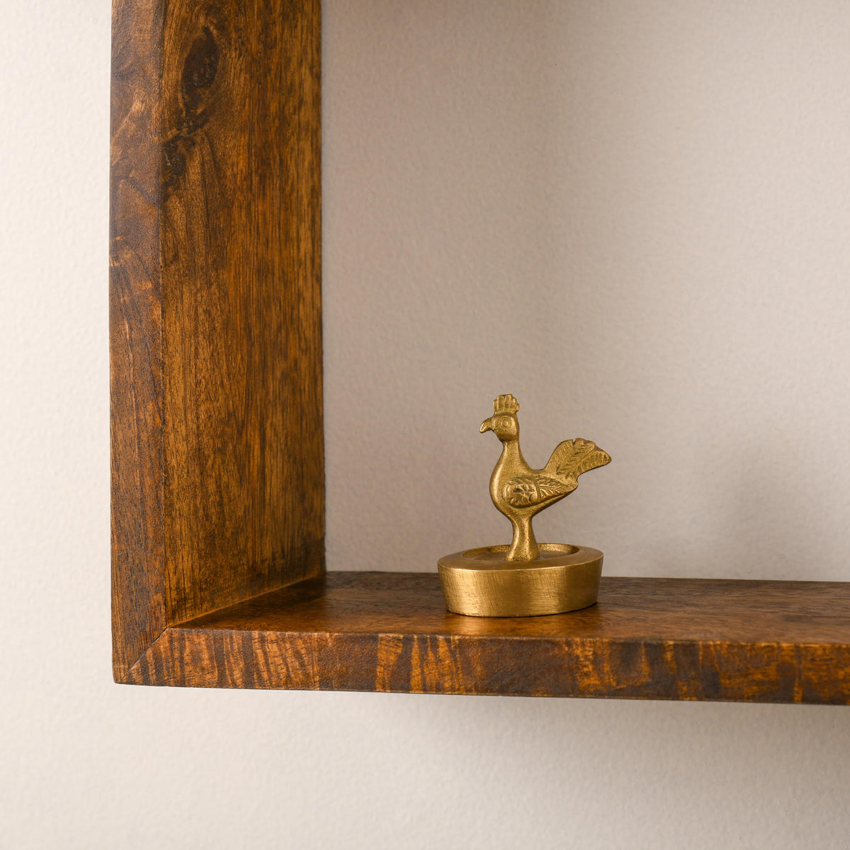WOOD CURLS solid mango wood wall shelf with a rich brown finish displaying a small decorative brass bird figurine