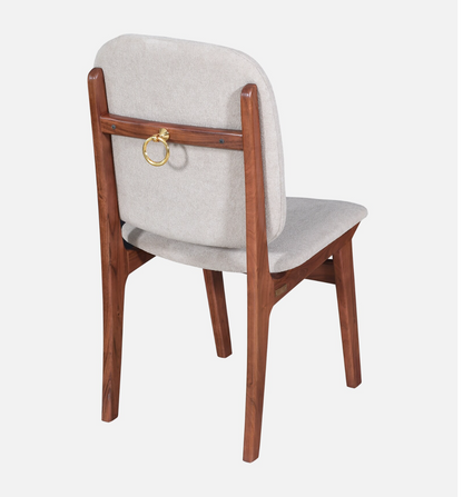 WOOD CURLS Marlow dining chair in acacia wood with light grey upholstery and a decorative gold ring on the backrest.