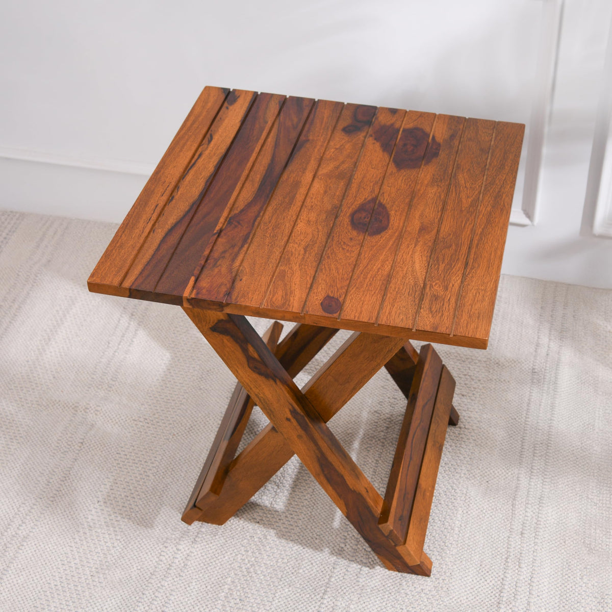 WOOD CURLS Nova square coffee table in natural Sheesham wood with a slatted top and folding cross-leg base.
