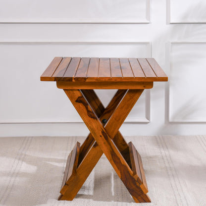 WOOD CURLS Nova square coffee table in natural Sheesham wood with a unique X-frame base against a white wall.