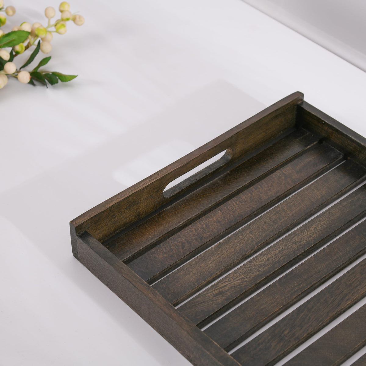 WOOD CURLS rectangular mango wood serving tray with a dark finish and cutout handles on a white surface.