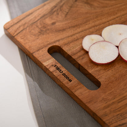 WOOD CURLS rectangular wooden chopping board with natural grain and handle, featuring sliced radishes on top.