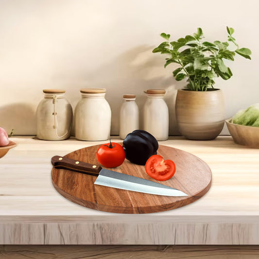 WOOD CURLS round acacia wood chopping board with a kitchen knife and fresh tomatoes on a wooden countertop.