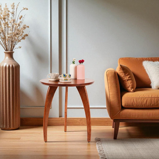 WOOD CURLS round mango wood coffee table with a natural finish in a cozy living room next to an orange sofa.