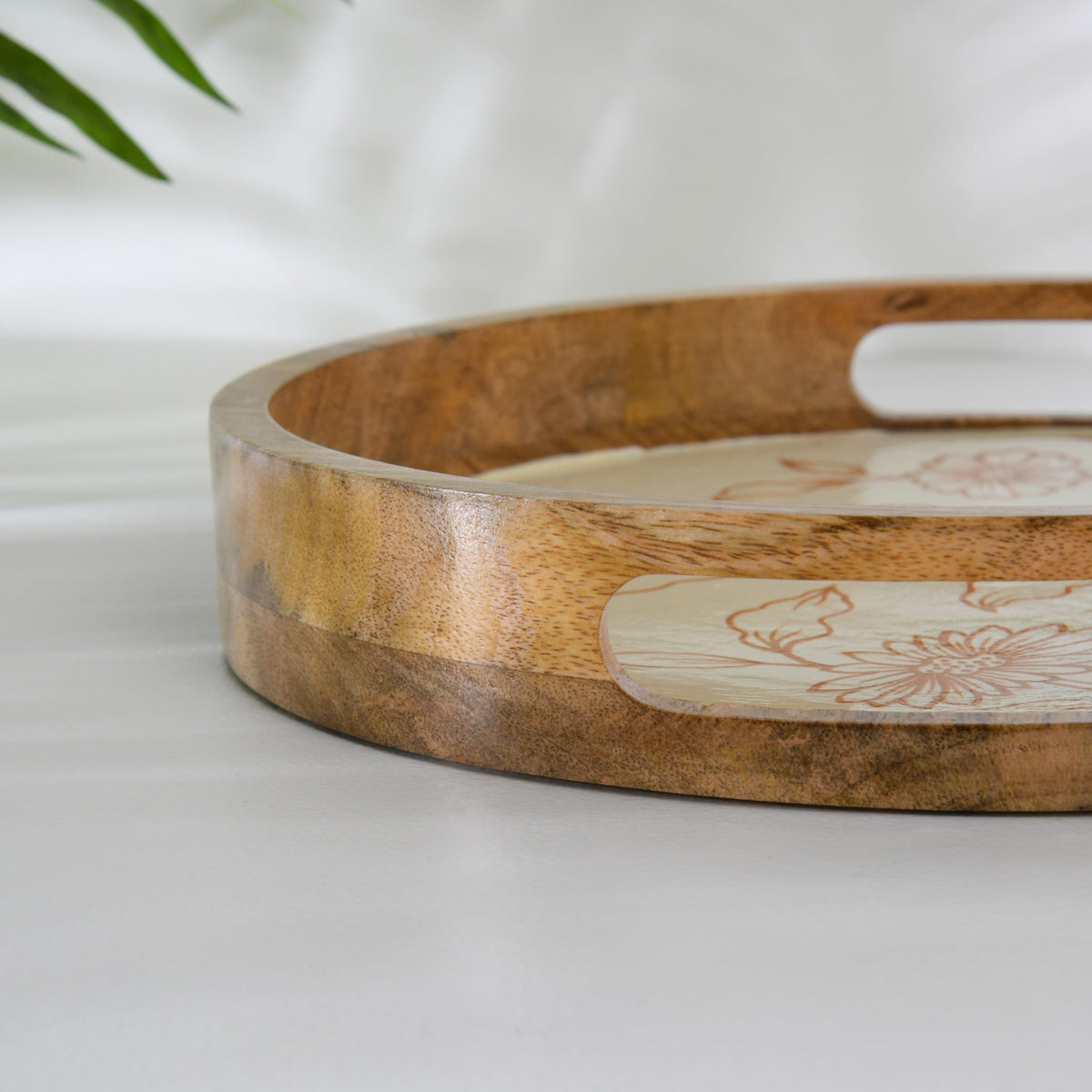 WOOD CURLS round mango wood serving tray with cream base and copper-toned hand-painted floral design and handles.