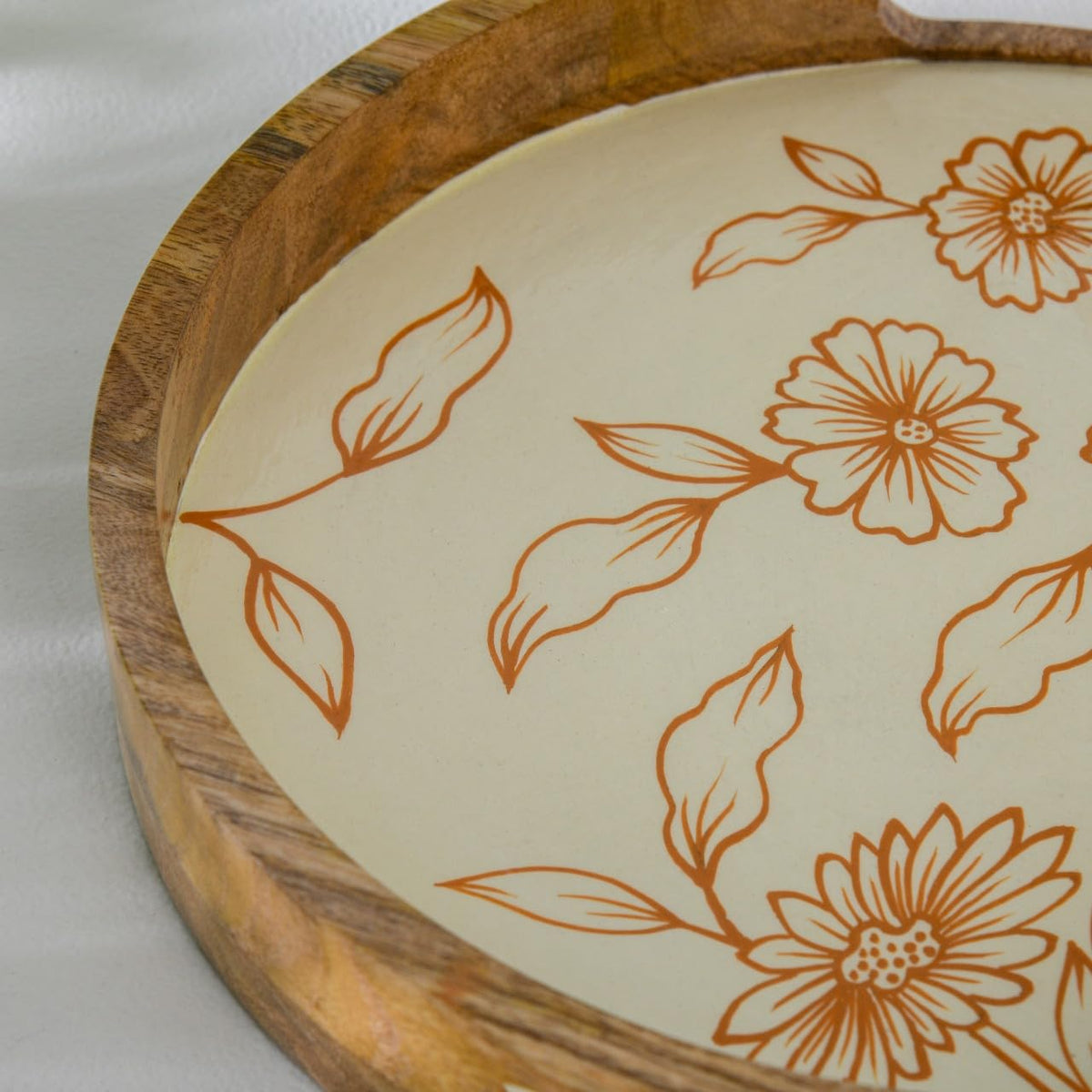 WOOD CURLS round mango wood serving tray with a cream base and hand-painted copper floral patterns and leaf motifs.