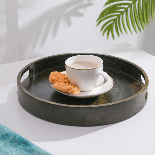 WOOD CURLS round mango wood serving tray in walnut finish with ergonomic handles holding a coffee cup and cookies
