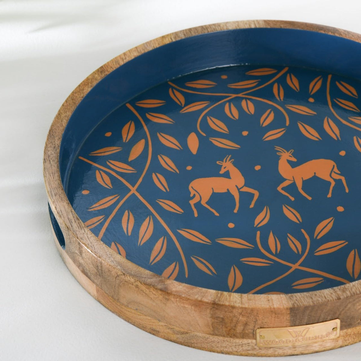 WOOD CURLS round mango wood serving tray with navy blue base, copper antelope and leaf motif, and rustic wood rim.