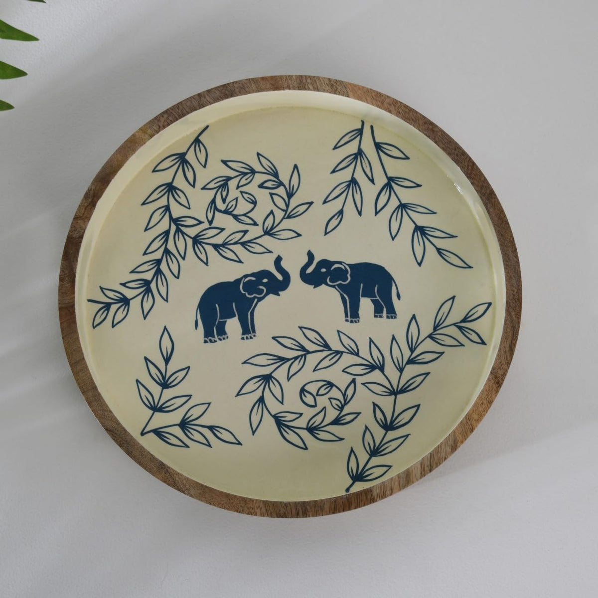WOOD CURLS round wooden serving tray with hand-painted blue elephant and leaf motifs on a cream background