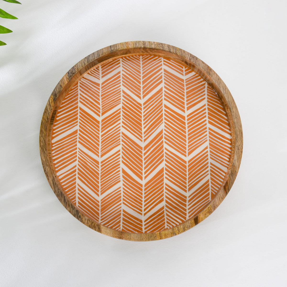 WOOD CURLS round wooden serving tray with a peach and white geometric herringbone enamel base and raised edges.