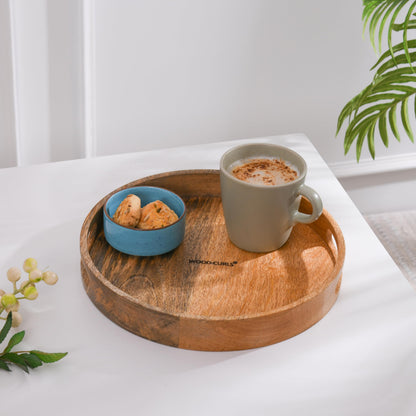 WOOD CURLS round wooden serving tray with a natural brown finish holding a coffee mug and a small bowl of cookies.
