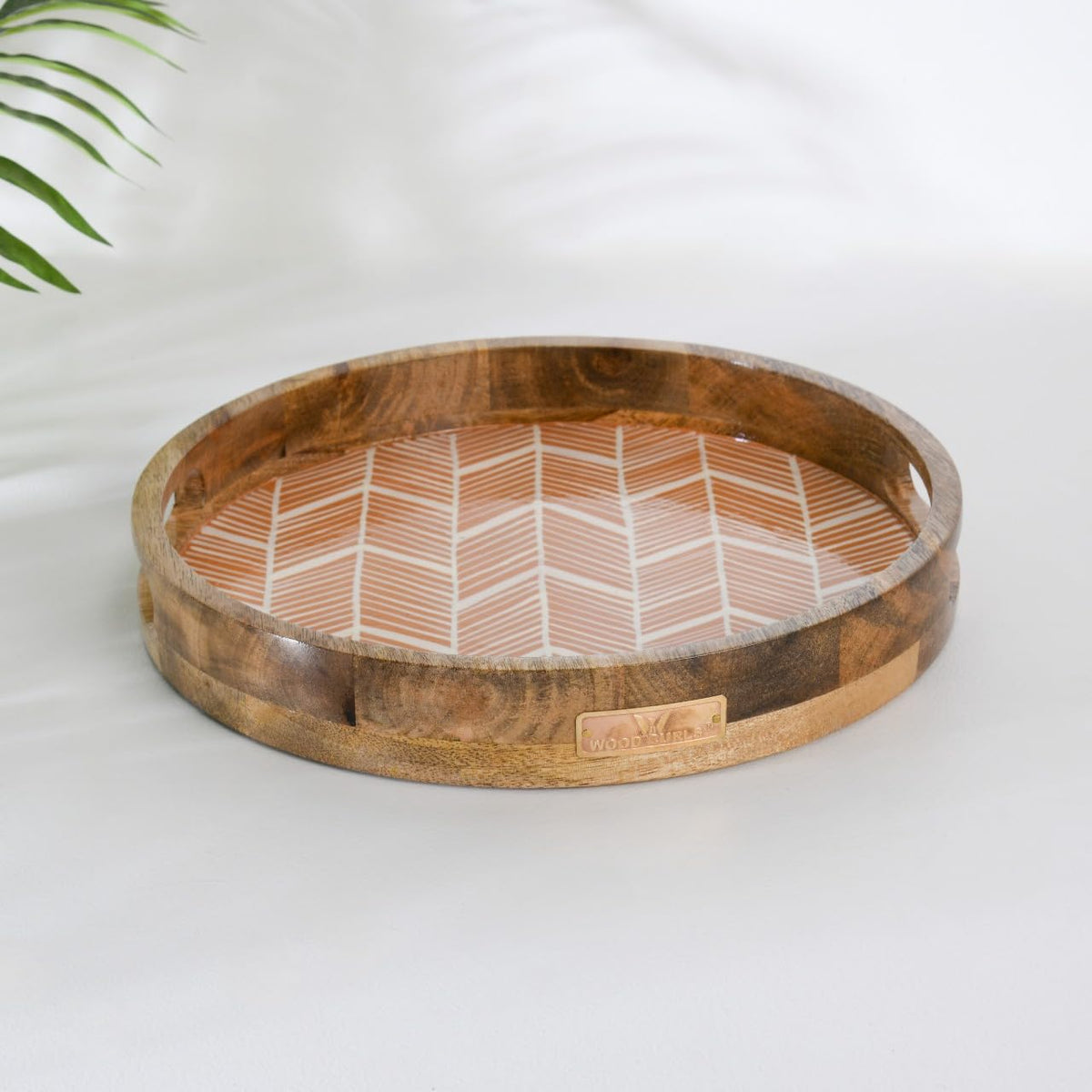 WOOD CURLS round wooden serving tray with a peach geometric herringbone enamel base and natural wood grain finish.