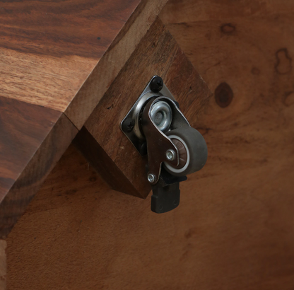 WOOD CURLS solid Sheesham wood bar cabinet base featuring a durable locking caster wheel for easy mobility.