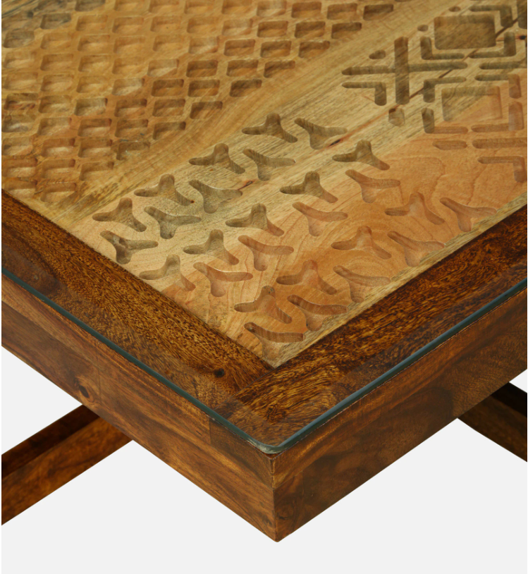 WOOD CURLS Quadra Sheesham wood coffee table with intricate carved patterns under a glass top in a rich walnut finish.