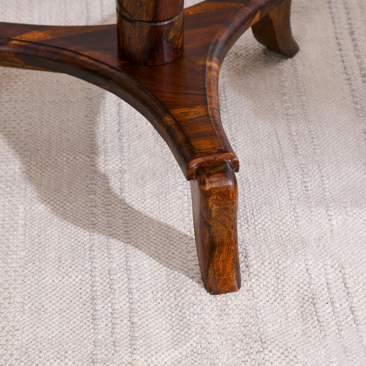 WOOD CURLS Xenith round end table featuring a curved pedestal base crafted from rich brown natural Sheesham wood.