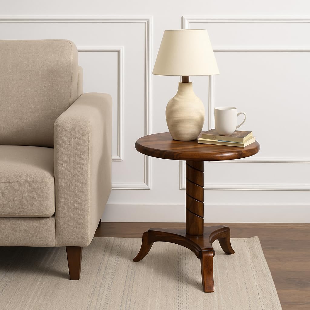 WOOD CURLS round end table in natural Sheesham wood with a pedestal base, styled with a lamp and mug next to a sofa.