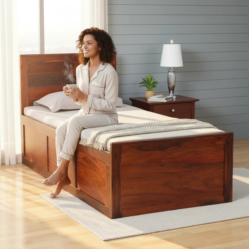 WOOD CURLS single bed in honey oak finish made of solid Sheesham wood with box storage, featuring a woman sitting on it.