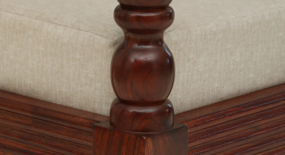 Close-up of WOOD CURLS Auburn three seater sofa featuring carved dark Sheesham wood armrest and beige fabric cushion.