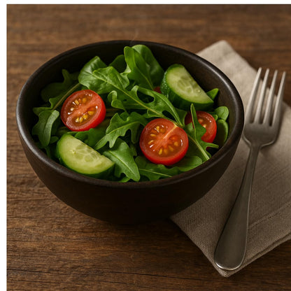 WOOD CURLS small dark brown mango wood serving bowl filled with a fresh salad of arugula, cucumber, and cherry tomatoes.