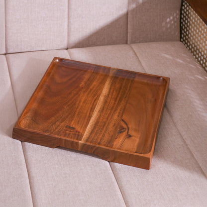 WOOD CURLS square mango wood serving platter with a natural grain finish, displayed on a neutral upholstered chair.
